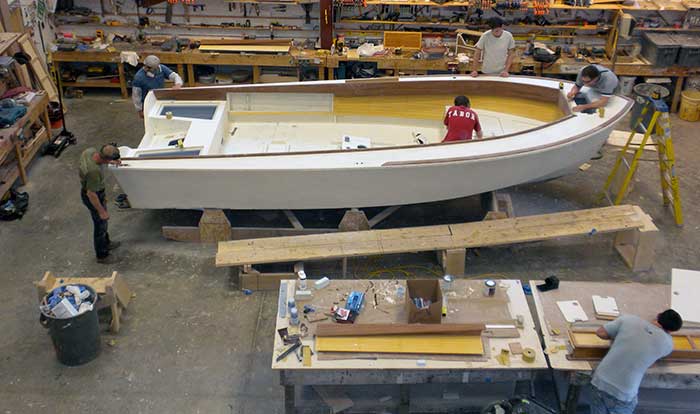 Four men in a warehouse building a boat