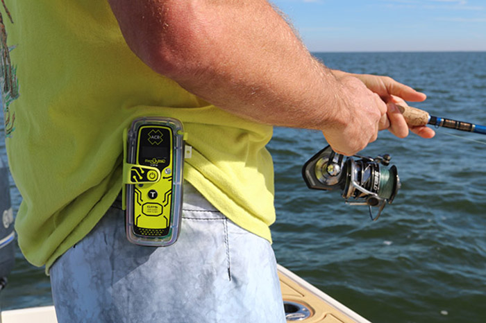 Adult in a yellow shirt with a yellow cellphone on his belt fishing.