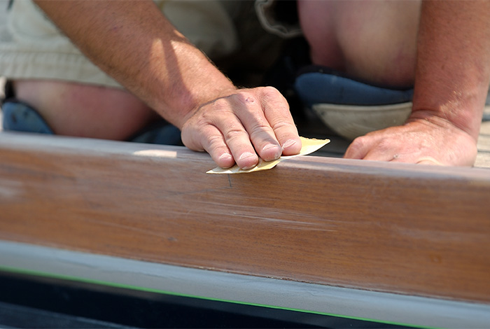 Adult sanding a rail on the boat.