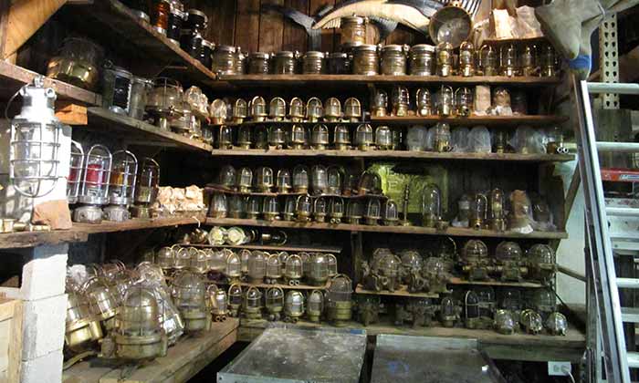 Several shelves of old boat lights are displayed. Most are old and covered in dust.