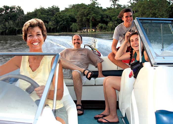 A family aboard a powerboat with a woman behind the helm