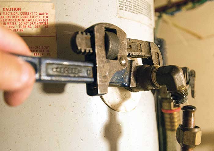 Using pipe wrench to unscrew hot water outlet