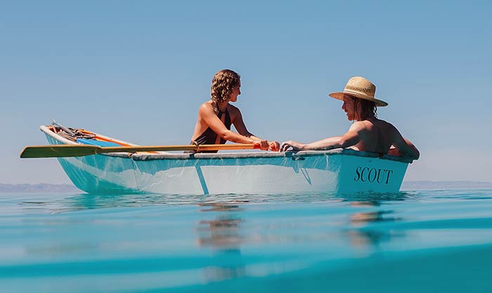 A man and woman in a white rowboat named SCOUT