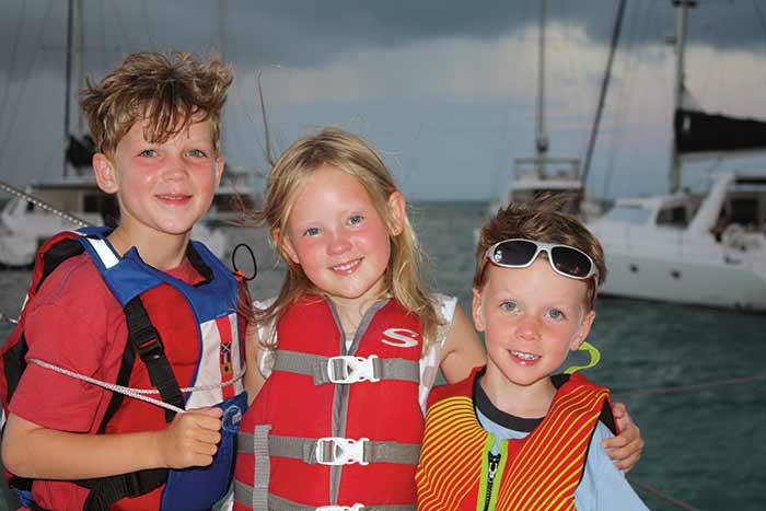 Three kids in lifejackets smiling at the camera