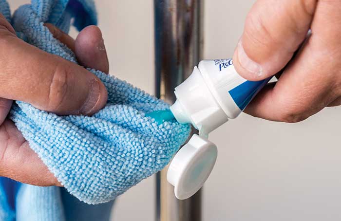 Squirting a tube of toothpaste onto a blue microfiber cloth