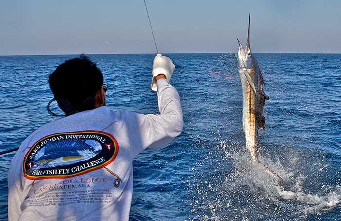 Man catching a sailfish while the sailfish appaers to walk with it's tail on the water