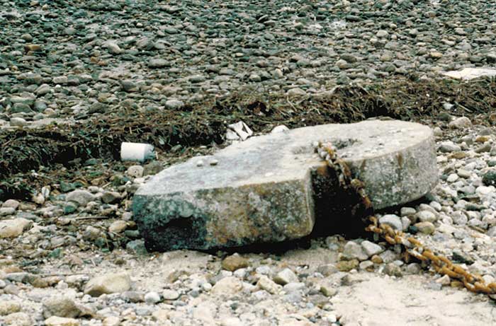 A large circular slab of concrete known as a morring attached to a rusty chain washed ashore