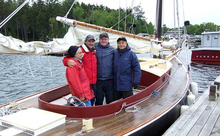 Three men and one woman posing in a sailboat in rainy weather