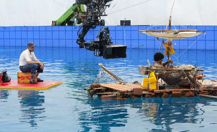 Camera hovering over wave tank filming actor on a raft