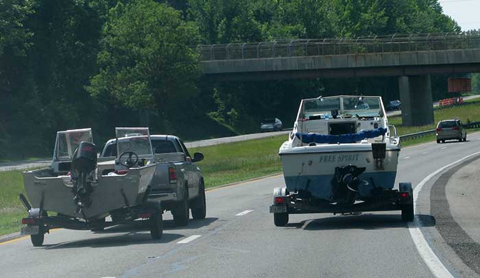 Two vehicles on the highway side-by-side towing powerboats