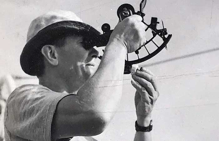 Man holding a sextant to his left eye to navigate using the stars while at sea