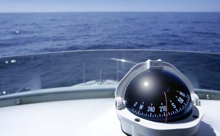 Compass on the helm of a boat as it cruises along the water