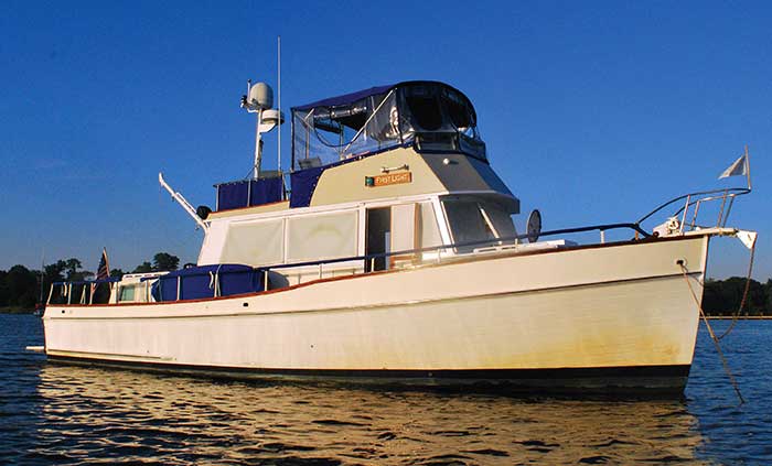 A white-colored Grand Banks 42 trawler named "First Light" moored out on the water