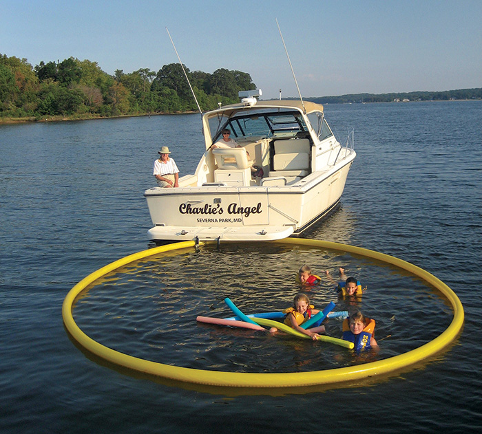Four children swimming within a yellow boat pool net next to a white vessel.