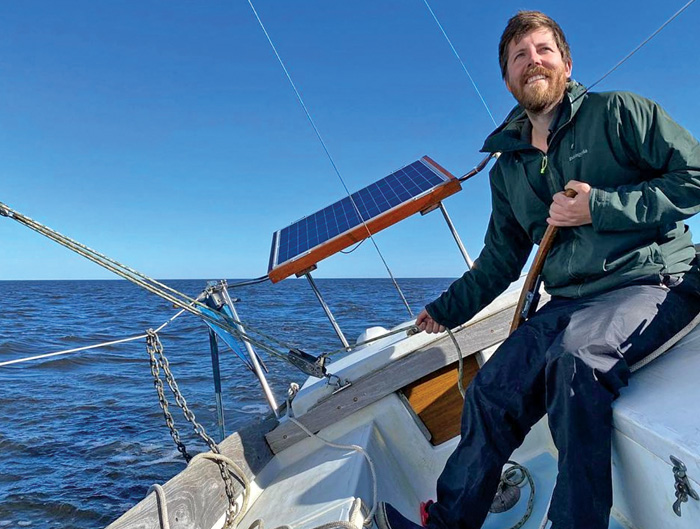 Middle-aged bearded man wearing a green jacket sailing in the open waters