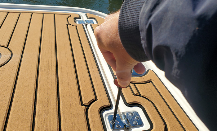 Hand pointing to fittings on a boat that need to be screwed in tighter.
