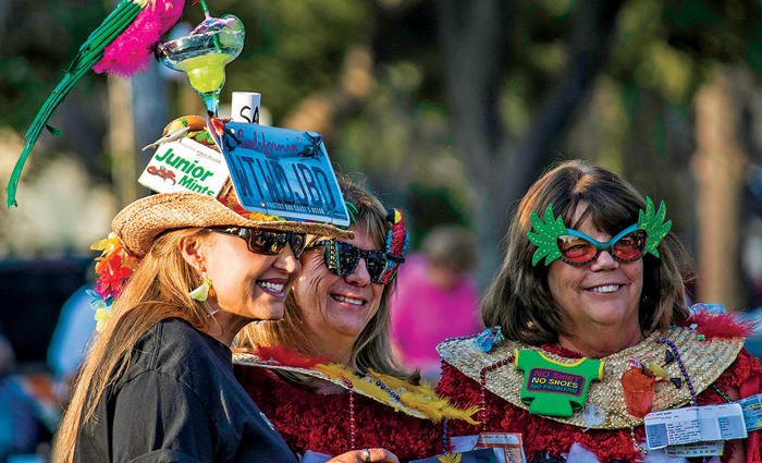 Three adult women dressed as "parrot heads" on a sunny day