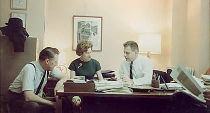 Three people in an old office discussing business