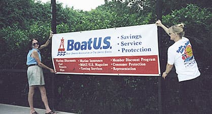 Two women putting up a BoatUS banner