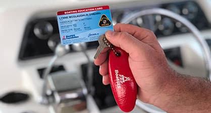 A man holding his boatus education card on his boat
